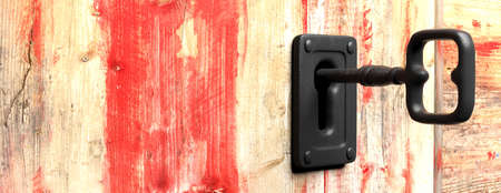 Key in a keyhole on red wooden background, copy space. 3d illustrationの写真素材