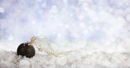 Christmas ball on abstract cold winter background with snow and defocused lightsの写真素材