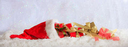Red Christmas gift boxes and santas hat on abstract cold winter background with snowの写真素材