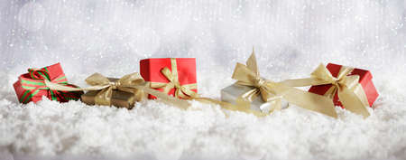 Red Christmas gift boxes on abstract cold winter background with snowの写真素材