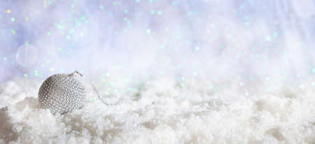 Christmas ball on abstract cold winter background with snow and defocused lightsの写真素材