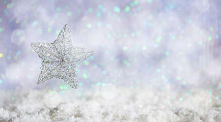 Christmas star on abstract cold winter background with snow and defocused lightsの写真素材