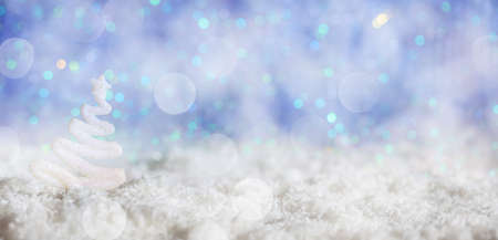 White Christmas tree on abstract cold winter background with snow and defocused lightsの写真素材