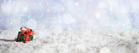 Christmas gift box on abstract cold winter background with snow and defocused lightsの写真素材