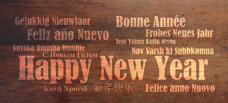 Happy new year wish in many languages on wooden backgroundの写真素材