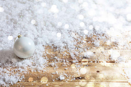 Christmas ball on a wooden table, snowy bokeh backgroundの写真素材