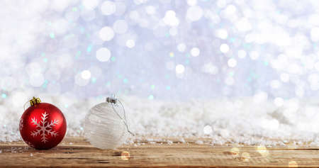 Christmas balls on a wooden table, snowy bokeh backgroundの写真素材