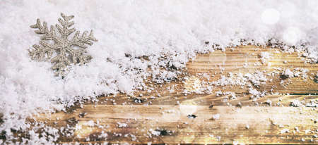 Christmas snowflake on a wooden table, snowy bokeh backgroundの写真素材