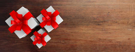 White gift boxes with red ribbons on wooden background, top view. 3d illustrationの写真素材