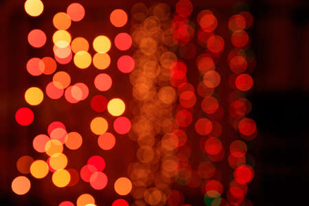 Christmas lights bokeh background. Orange, yellow and red lights on dark backgroundの写真素材