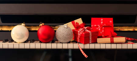 Chritmas balls and gift boxes on classical piano keyboard, front viewの写真素材
