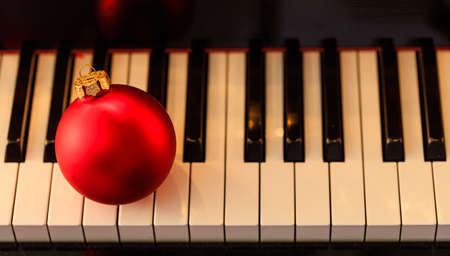 Red Christmas ball on a classical piano keyboard, above viewの写真素材