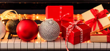 Chritmas balls and gift boxes on classical piano keyboard, front viewの写真素材