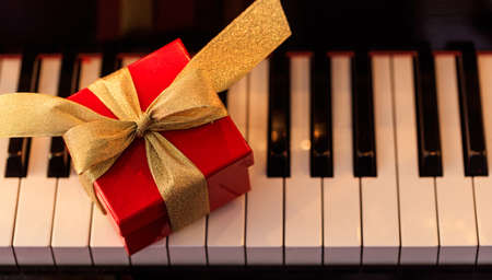 Red gift box on a classical piano keyboard, above viewの写真素材