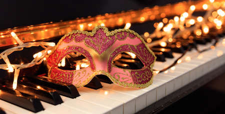 Carnival mask and lights on a classical piano keyboardの写真素材