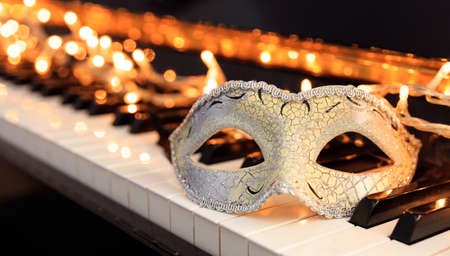 Carnival mask and lights on a classical piano keyboardの写真素材