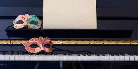 Carnival masks on classical piano keyboard, front viewの写真素材