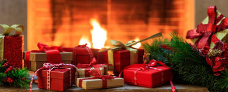 Christmas gift boxes close up on blurred burning fireplace backgroundの写真素材