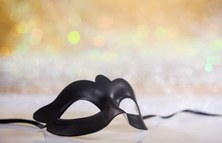 Black carnival mask on white surface, abstract bokeh backgroundの写真素材