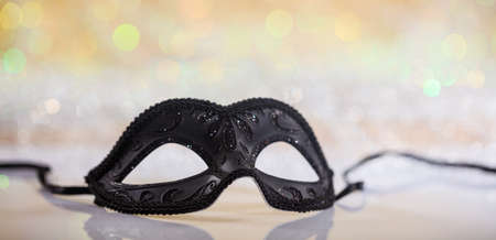 Black carnival mask on white surface, abstract bokeh backgroundの写真素材