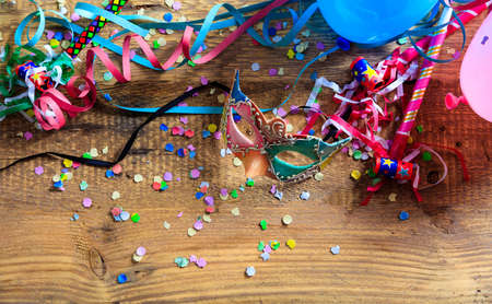 Carnival party. Mask, confetti and serpentines on wooden background, top niew, copy spaceの写真素材