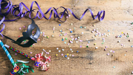 Carnival party. Black mask, confetti and serpentines on wooden background, top niew, copy spaceの写真素材