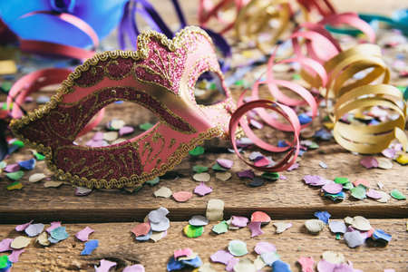 Carnival party. Mask, confetti and serpentines on wooden background, front viewの写真素材