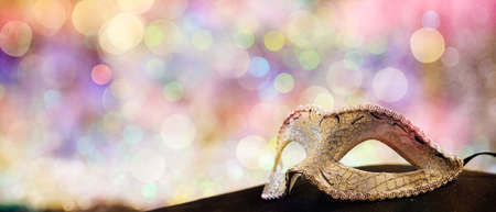Silver carnival mask on black surface, colorful bokeh backgroundの写真素材