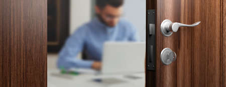 Office doorway with half opened door, blur emploee working on the background. 3d illustrationの写真素材