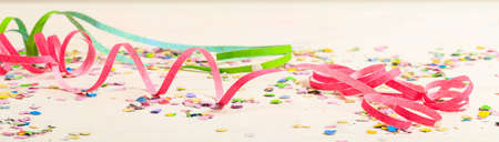 Colorful carnival confetti and serpentines on white wooden background, bannerの写真素材