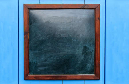 Blank wooden frame on the wall. Blackboard inside and light blue background, space for text.の写真素材
