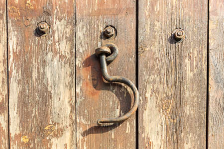 Rusty hook hanging on peeling wooden background. Close up view.の写真素材