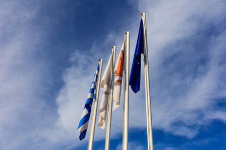 Cyprus, Greece, EU and Larnaka municipality flags on flagpoles. Cloudy sky background.の写真素材