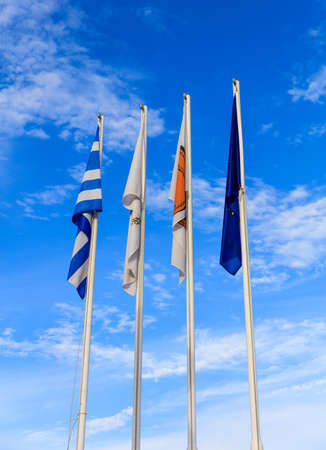 Cyprus, Greece, EU and Larnaka municipality flags on flagpoles. Cloudy sky background.の写真素材