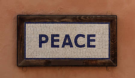 Word peace made from cubes. Mosaic pattern, wooden frame, salmon color background. Close up view.の写真素材