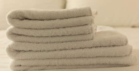 Hotel bedroom. White fluffy, folded towels, linen beddings on tidy bed. Close up view, details.の写真素材