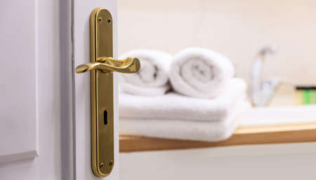 Bathroom from open door. Blur white towels folded next to the sink. Blur backdrop, details of door.の写真素材