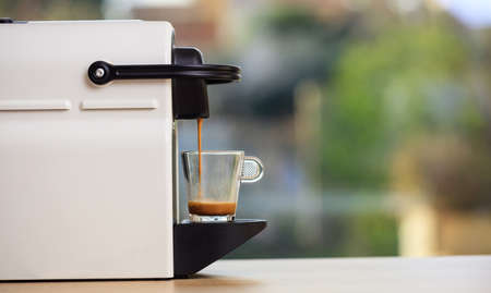 Making espresso. Espresso coffee maker on a wooden table. Blurred background, space for text, front viewの写真素材