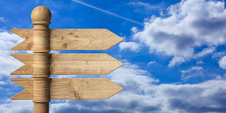 Blank wooden arrow signposts on metal pole, isolated on blue sky background. 3d illustrationの写真素材