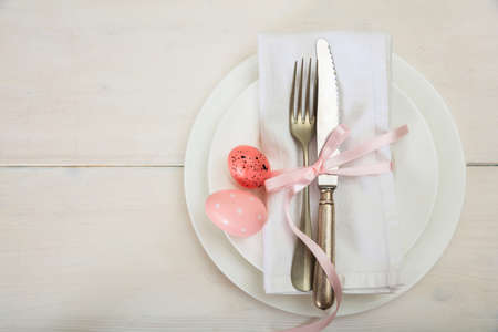 Easter table setting on white wooden background. Top view, space for text