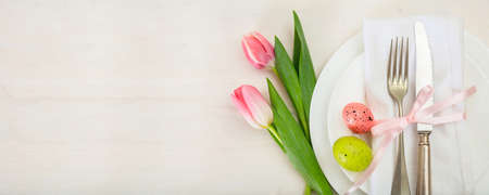 Easter table setting with pink tulips on white wooden background. Top view, banner, space for textの写真素材