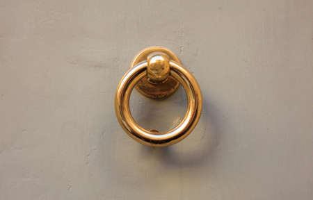 Old brass door knocker, ring shape, on a gray painted front doorの写真素材