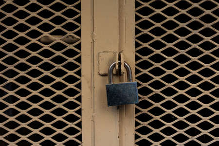 Locked door. Closed padlock on an old yellow metal door, closeup viewの写真素材