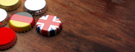 UK and Germany. Beer caps with UK and Germany flags on wooden background, copy space, banner. 3d...