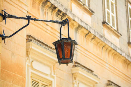 Mdina, Malta island. Old lantern lamp in the medieval city with the narrow streets and houses sandstone facadesの写真素材
