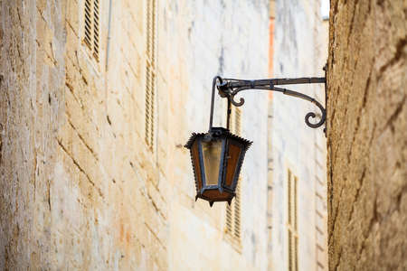 Mdina, Malta island. Old lantern lamp in the medieval city with the narrow streets and houses sandstone facadesの写真素材