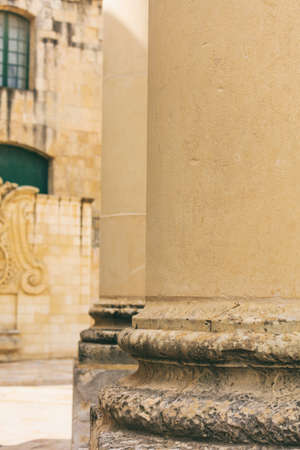 Sandstone columns detail in the city center. Blur yellow building facade background. Valletta, Malta