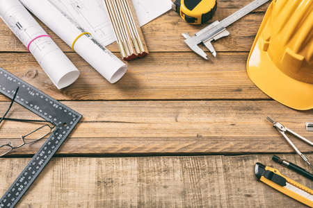 Architect workplace top view. Project construction blueprints and engineering tools on wooden desk, copy spaceの写真素材