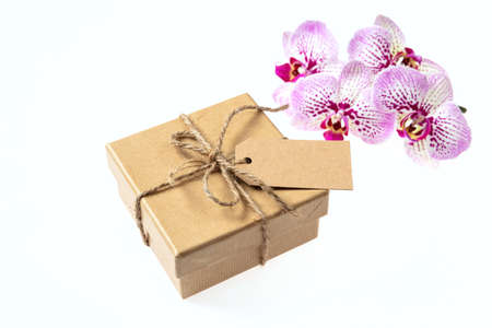 Orchid pink flowers and a gift box with a blank tag isolated on a white background, space for textの写真素材