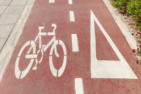 Bike lane. Bicycle sign and white directional arrow on red asphalt pathの写真素材